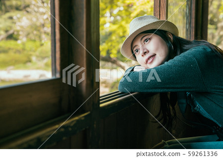 traveler wearing hat leaning against open window 59261336