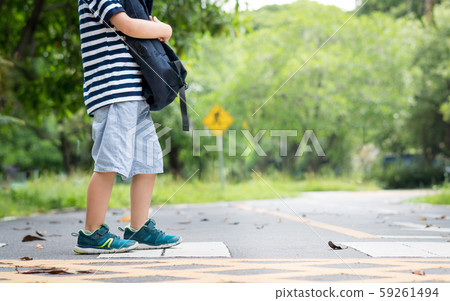 Closeup legs of a little child, kindergarten boy hold his backpack walking on pedestrian crossing to school by himself. Safety, Life skills, Speed limit, Drive carefully, School zone, Back to school. Closeup legs of a little child, kindergarten boy hold his backpack walking on pedestrian crossing to school by himself. Safety, Life skills, Speed limit, Drive carefully, School zone, Back to school. 59261494