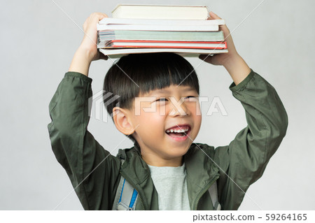 'Back to school' A lovely little boy having fun holding his lesson books on his head. Education, Smart kids, Child development, Genius, Kids Intelligence, High IQ, Emotional Quotient, IQ-EQ concept. 59264165