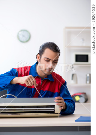 Young repairman repairing air-conditioner at warranty center Young repairman repairing air-conditioner at warranty center 59264539