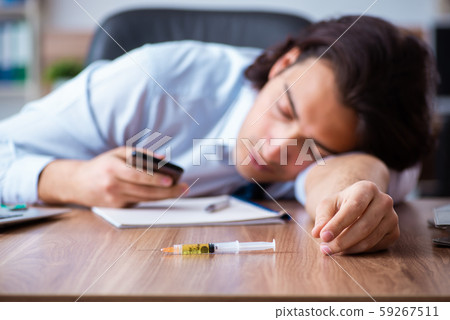 Young man having problems with narcotics at workplace 59267511
