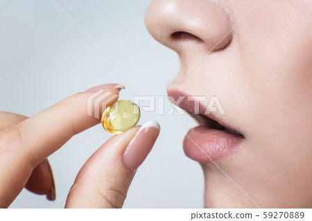 Close-up shot of woman brings the pill to her mouth. Close-up shot of woman brings the pill to her mouth. 59270889