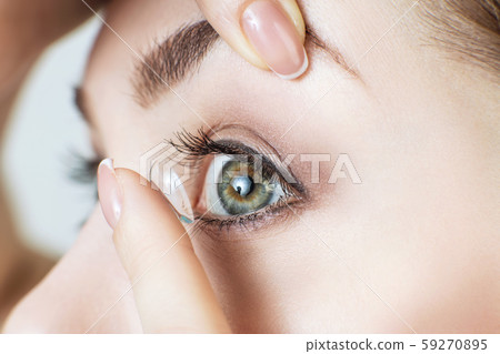 Close-up shot of young woman wearing contact lens. 59270895