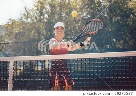 Woman in red sport dress playing tennis 59272587