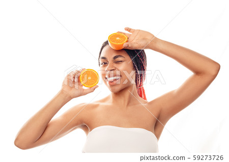 Beauty Concept. Young african woman wearing top isolated on white with orange halves posing showing Beauty Concept. Young african woman wearing top isolated on white with orange halves posing showing 59273726