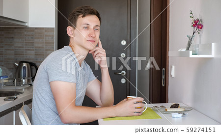 Young man traveler is having a breakfast in small kitchen at rented flat. 59274151