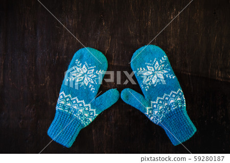 a pair of blue knitted mittens on a dark blue-green-brown wooden 59280187
