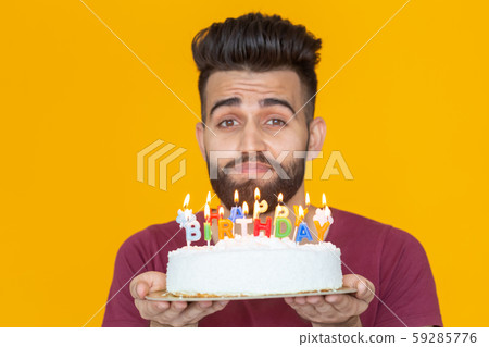 Portrait of a funny positive guy holding a congratulatory homemade cake in his hands on a yellow Portrait of a funny positive guy holding a congratulatory homemade cake in his hands on a yellow 59285776