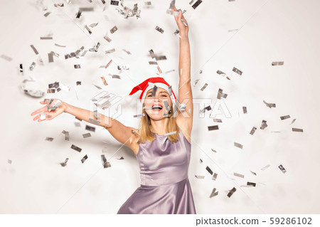 New year and holidays concept - Happy excited young woman in santa claus hat dancing and laughing New year and holidays concept - Happy excited young woman in santa claus hat dancing and laughing 59286102