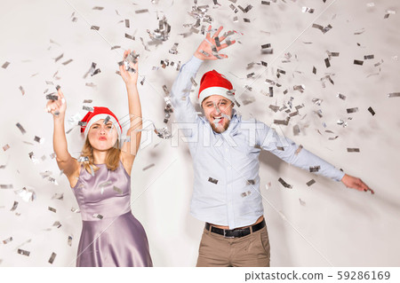 New year, christmas and party concept - Cheerful young people showered with confetti on a white New year, christmas and party concept - Cheerful young people showered with confetti on a white 59286169