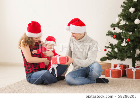 Happy couple with baby celebrating Christmas together at home. Happy couple with baby celebrating Christmas together at home. 59286203