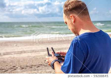 Man flying his drone by using a remote controller on the beach 59288645