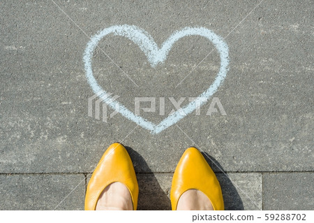 Female feet with symbol of the blue heart painted on the asphalt. 59288702