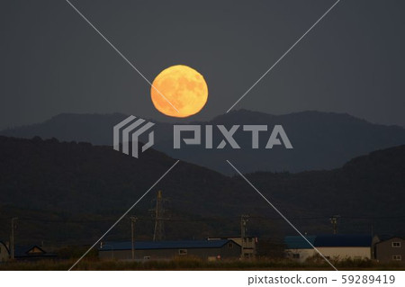 Take a picture of the full moon landscape just rising from a ridge that was distorted by temperature differences in Esashi, Hokkaido 59289419