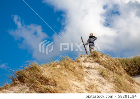 Young boy with stick standing on top of sand dune Young boy with stick standing on top of sand dune 59291184