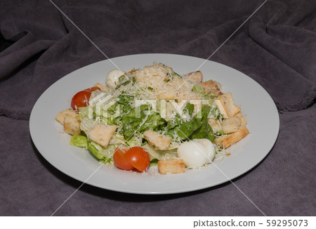 Caesar salad on a white plate and a dark 59295073
