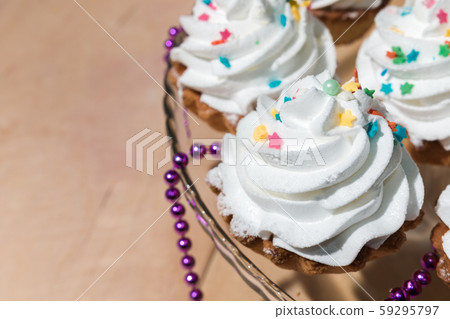 Cakes with white cream and colored powder on a 59295797