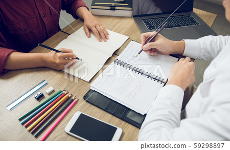 Two student reading textbook for test together in Two student reading textbook for test together in 59298897