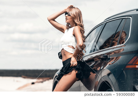 Charming sexy woman on tiptoe leaning on car on 59300080