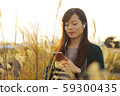 A woman who walks while listening to music in the field of Suki 59300435