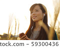 A woman who walks while listening to music in the field of Suki 59300436