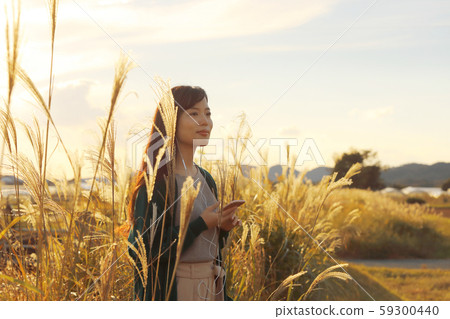 A woman who walks while listening to music in the field of Suki A woman who walks while listening to music in the field of Suki 59300440