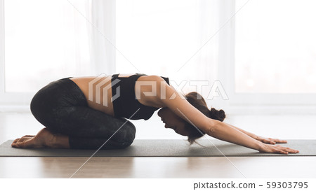 Fitness, woman meditating in child's pose at home Fitness, woman meditating in child's pose at home 59303795