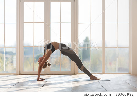 Acrobatic girl making bridge over big panoramic window Acrobatic girl making bridge over big panoramic window 59303982