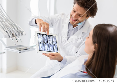 Handsome doctor showing patient x-ray result on digital tablet 59304075