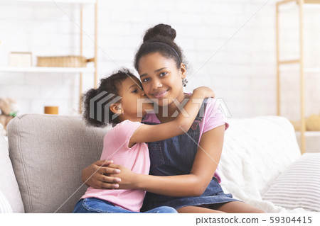 Little african girl kissing her elder sister at home Little african girl kissing her elder sister at home 59304415