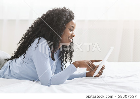 Beautiful afro girl serfing internet on digital tablet Beautiful afro girl serfing internet on digital tablet 59307557