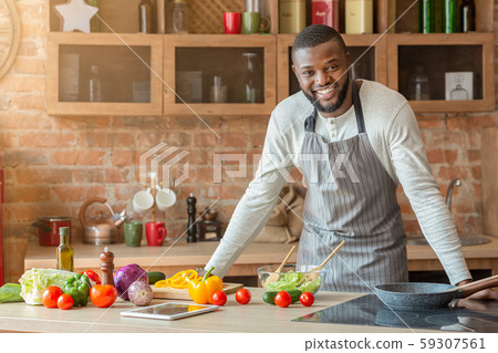 Attractive black man posing at kitchen while cooking 59307561