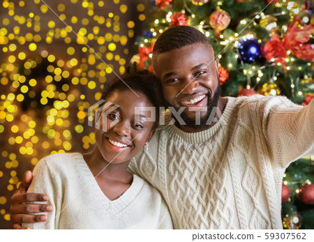 Happy black couple making selfie with Christmas tree on background 59307562