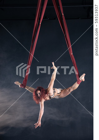 Female athletic, sexy and flexible aerial circus artist with redhead dancing in the air on the silk 59313937