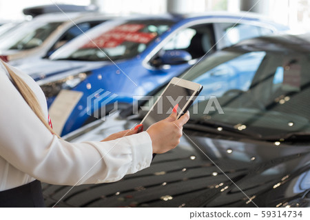 Woman using digital tablet at dealer showroom. 59314734