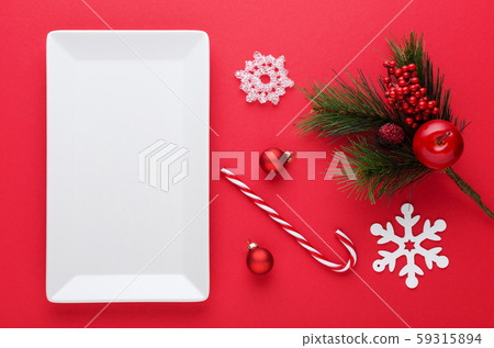 christmas table decoration with a white plate, baubles, snowflakes and candy cane on red 59315894