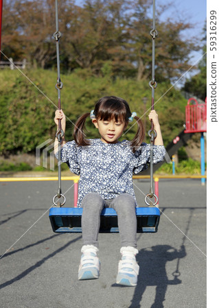 Infant playing on a swing (5-year-old) 59316299