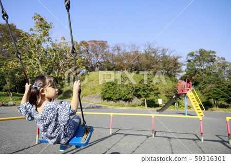 Toddler in the back playing with a swing (5-year-old child) 59316301