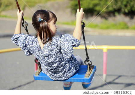 Toddler in the back playing with a swing (5-year-old child) 59316302
