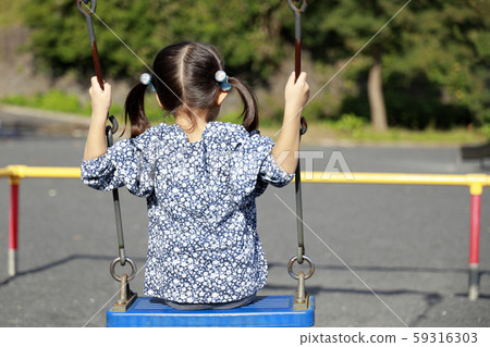 Toddler in the back playing with a swing (5-year-old child) 59316303
