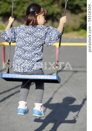 Toddler in the back playing with a swing (5-year-old child) 59316304
