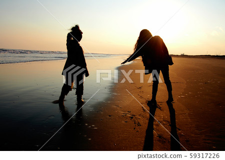 兩個女人站在海邊，在日落時 59317226