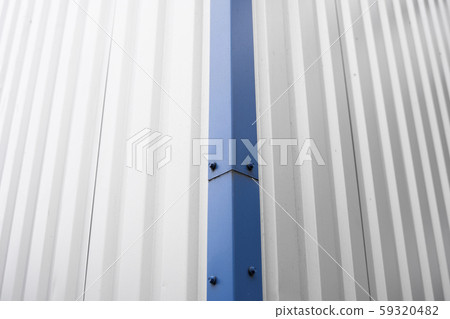 Metal corrugated sheets on a building with a blue metal corners. White aluminium metal corrugated 59320482