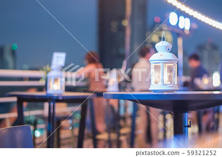 Romantic white candle light lamp illumination with fire burning brightly in blur dark dinner party restaurant background. 59321252
