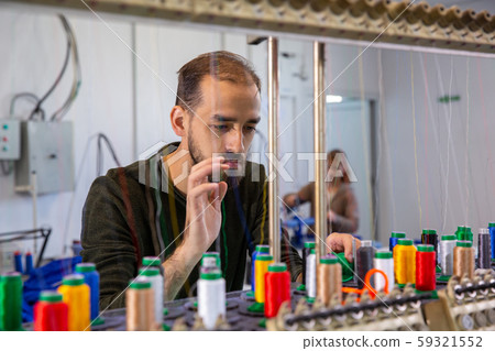 Young worker at the tailor's factory who controls the spools 59321552