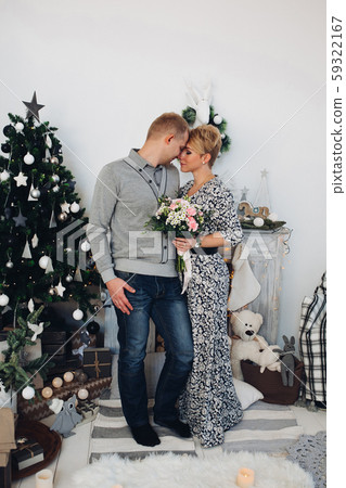 Beautiful couple with bouquet at Christmas tree. Beautiful couple with bouquet at Christmas tree. 59322167