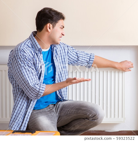 Young repairman contractor repairing heating panel Young repairman contractor repairing heating panel 59323522