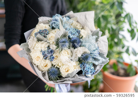 White and blue color. Beautiful bouquet of mixed flowers in womans hands. the work of the florist at White and blue color. Beautiful bouquet of mixed flowers in womans hands. the work of the florist at 59326595
