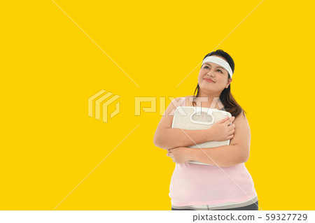 Overweight Asian woman with scale on yellow background Overweight Asian woman with scale on yellow background 59327729