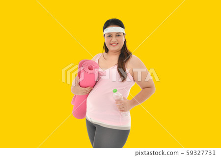Overweight Asian woman with exercise mat on yellow background Overweight Asian woman with exercise mat on yellow background 59327731